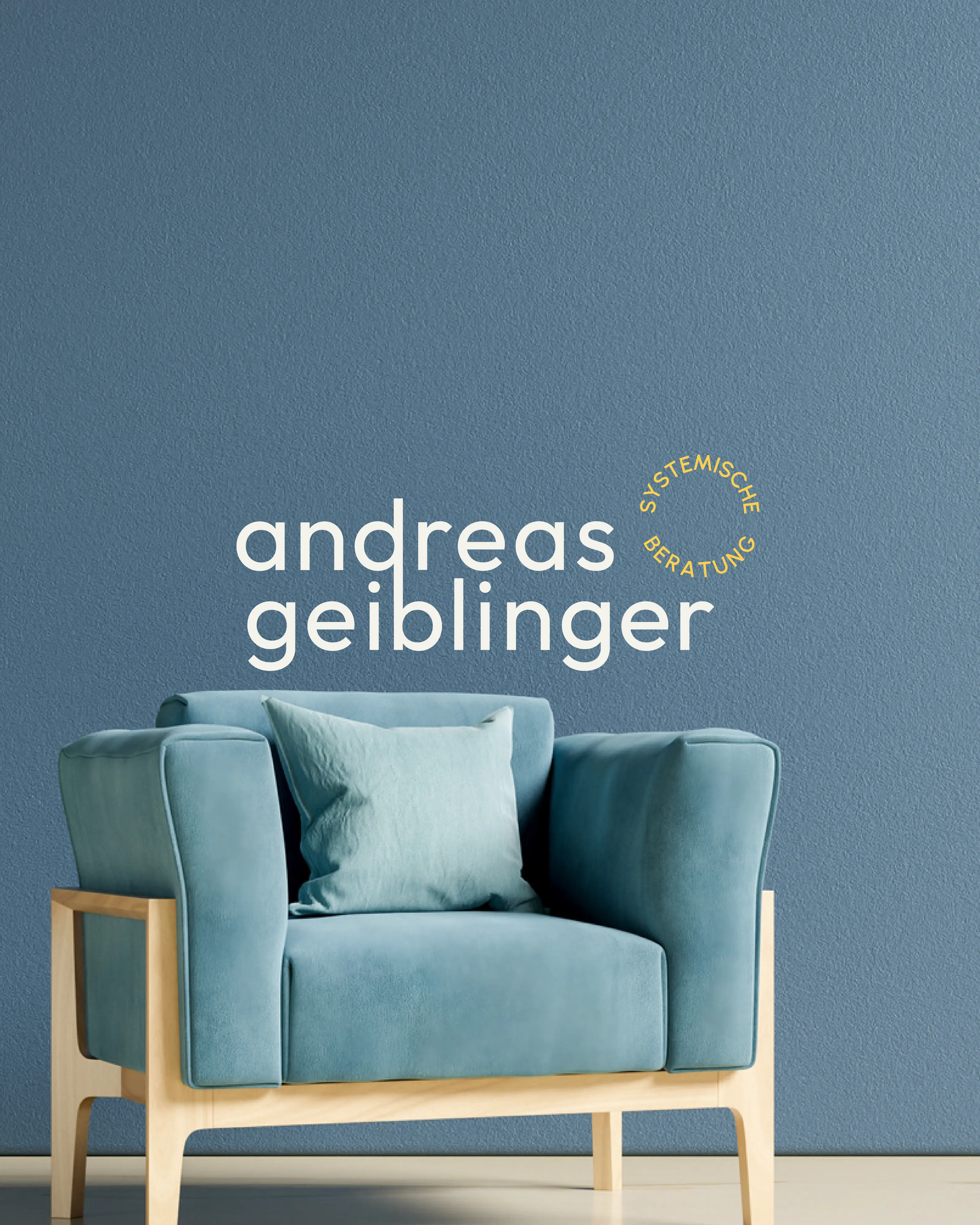 Logo Andreas Geiblinger an einer blauen Wand über einem Sessel, madea