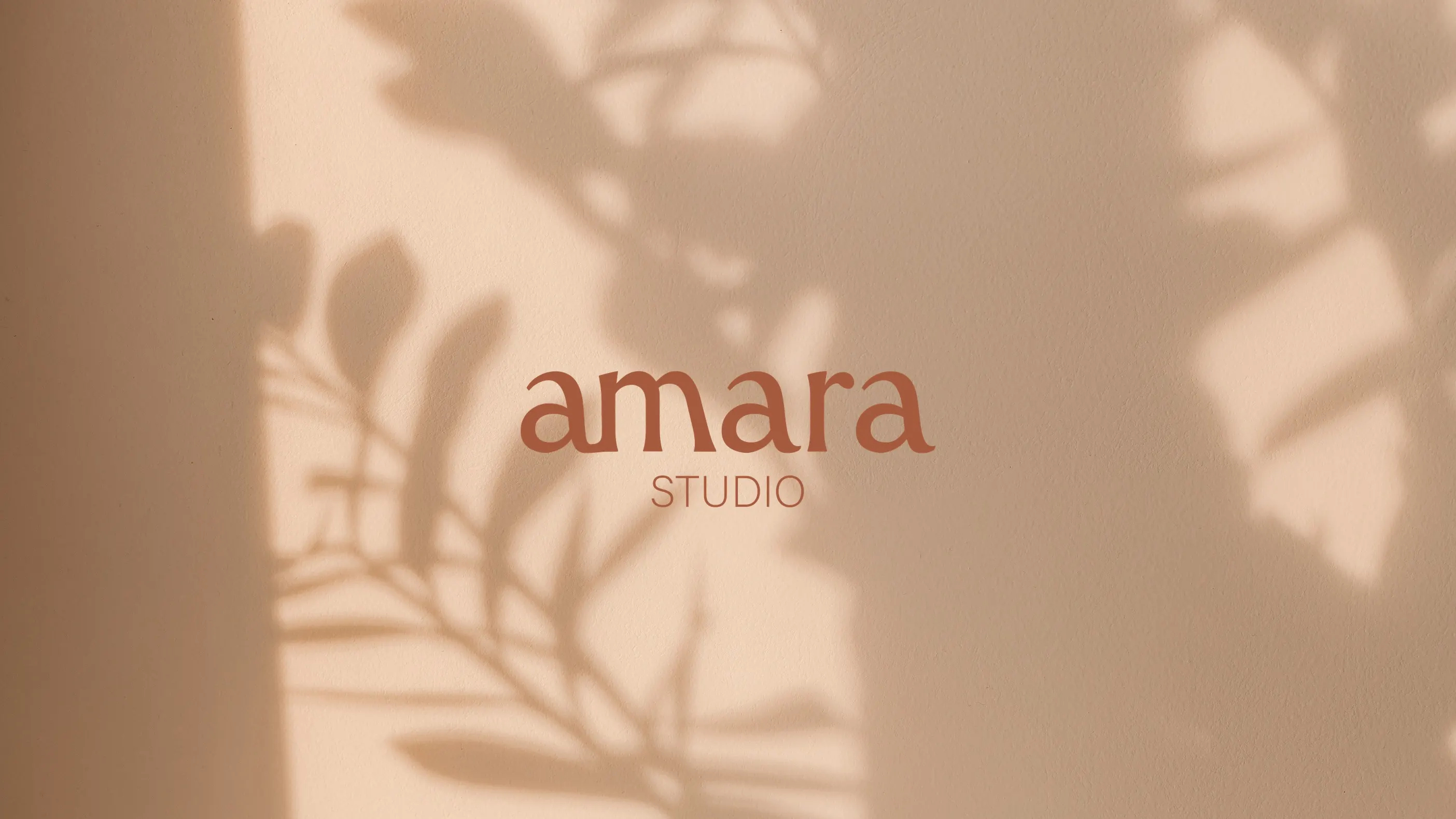 Wortmarke studio amara auf Sand mit dem Schatten einer Pflanze, madea