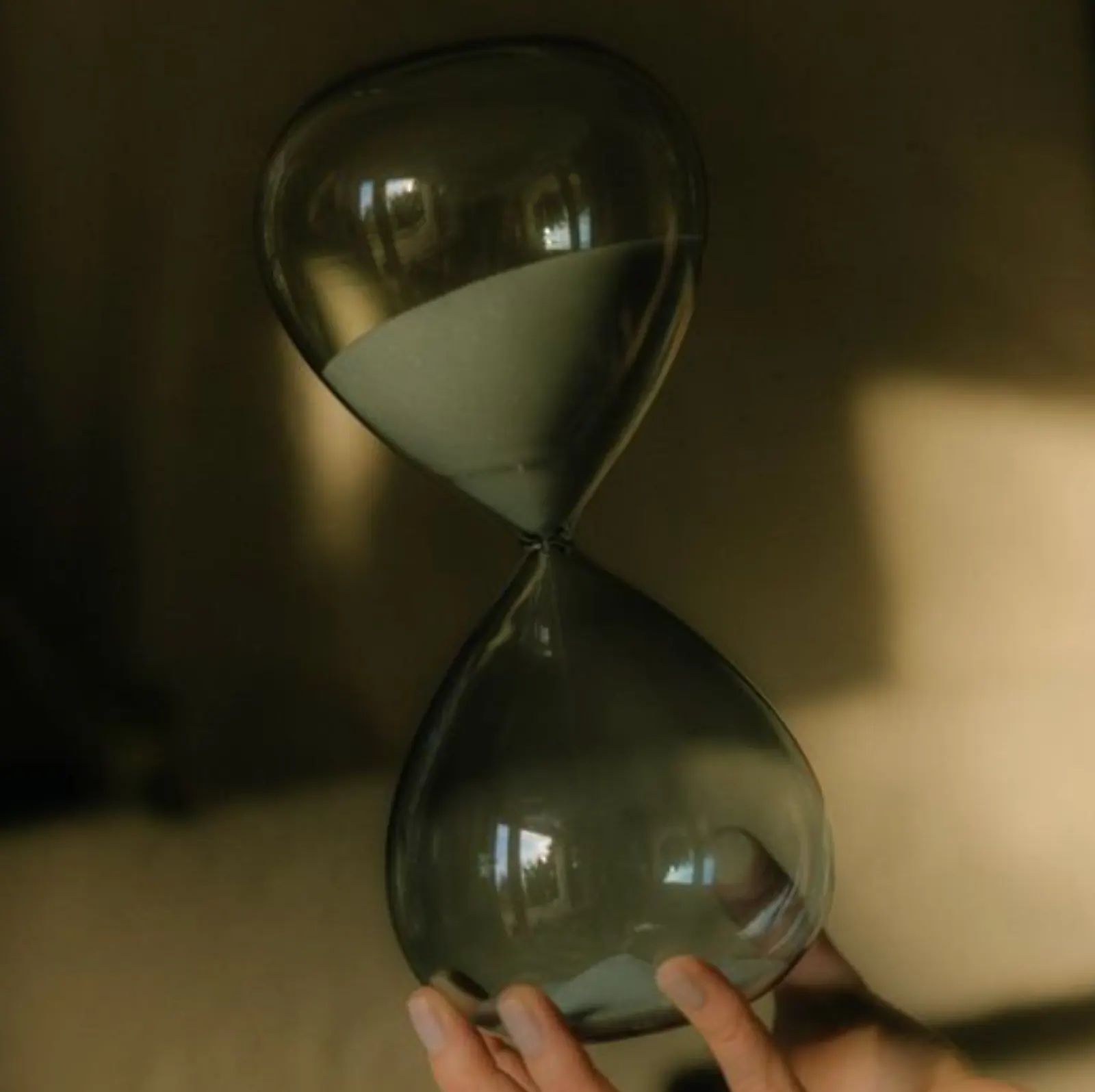 Sanduhr in einer Hand vor dunklem Hintergrund, Stimmungsbild, madea